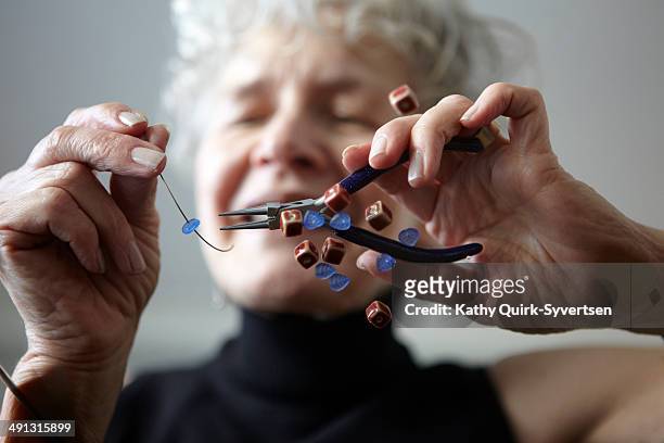 senior woman making jewelry with beads - hacer cuentas fotografías e imágenes de stock
