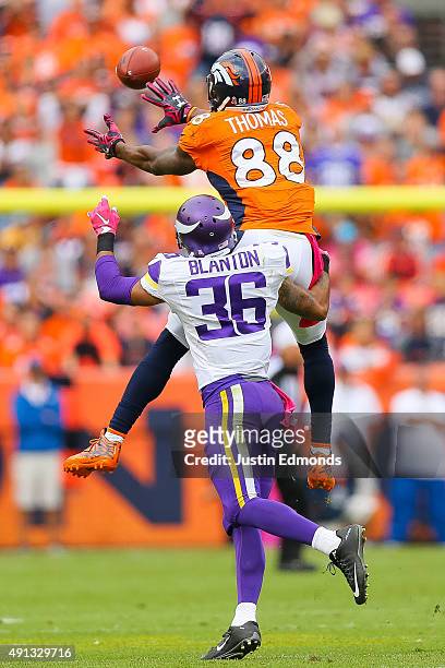 Wide receiver Demaryius Thomas of the Denver Broncos leaps to make a catch under coverage by strong safety Robert Blanton of the Minnesota Vikings...