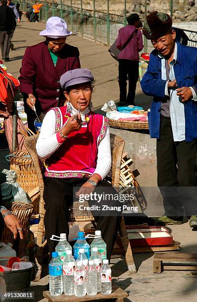 Lisu woman is selling white wine in mineral-water bottles. The Lisu Autonomous Prefecture of Nujiang, located in the northwest of Yunnan province...