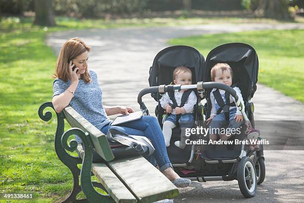 mother working from the park with her young family - baby pram in the park stock-fotos und bilder