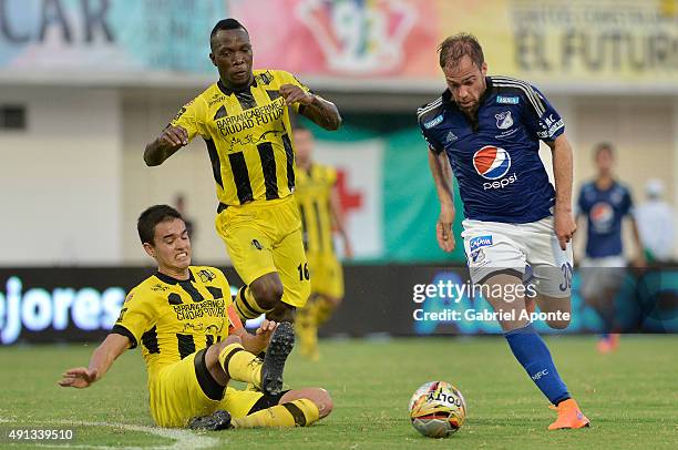 Federico Insua of Millonarios drives the ball as Felipe Aguilar of Alianza Petrolera slides during a match between Alianza Petrolera and Millonarios...