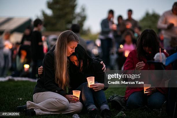 Heidi Wickersham, left, wipes away her tears while consoling her sister, Gwendolyn Wickersham, center, a UCC student who is grieving for her creative...