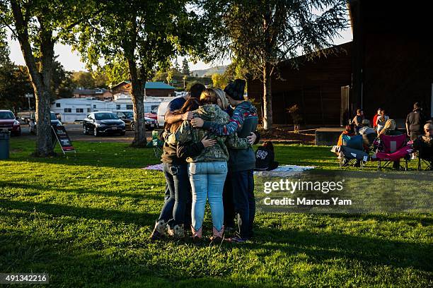 Friends of the late Rebecka Ann Carnes, an Umpqua Community College mass shootings victim, embrace one another in prayer before the start of a...
