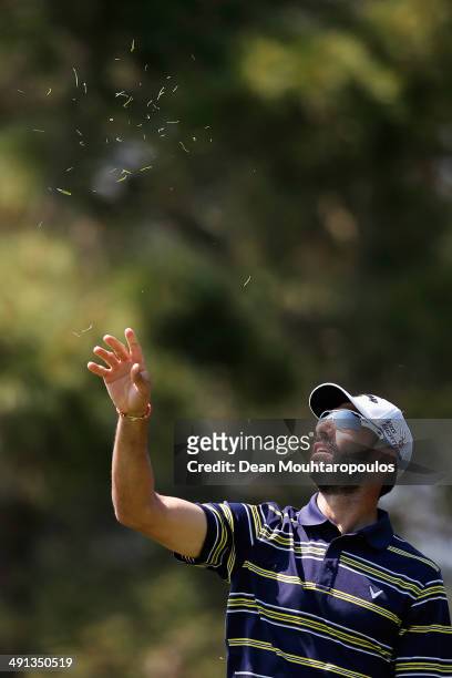 Alvaro Quiros of Spain throws grass in the air to judge the wind direction before he hits his second shot on the 10th hole during Day 2 of the Open...