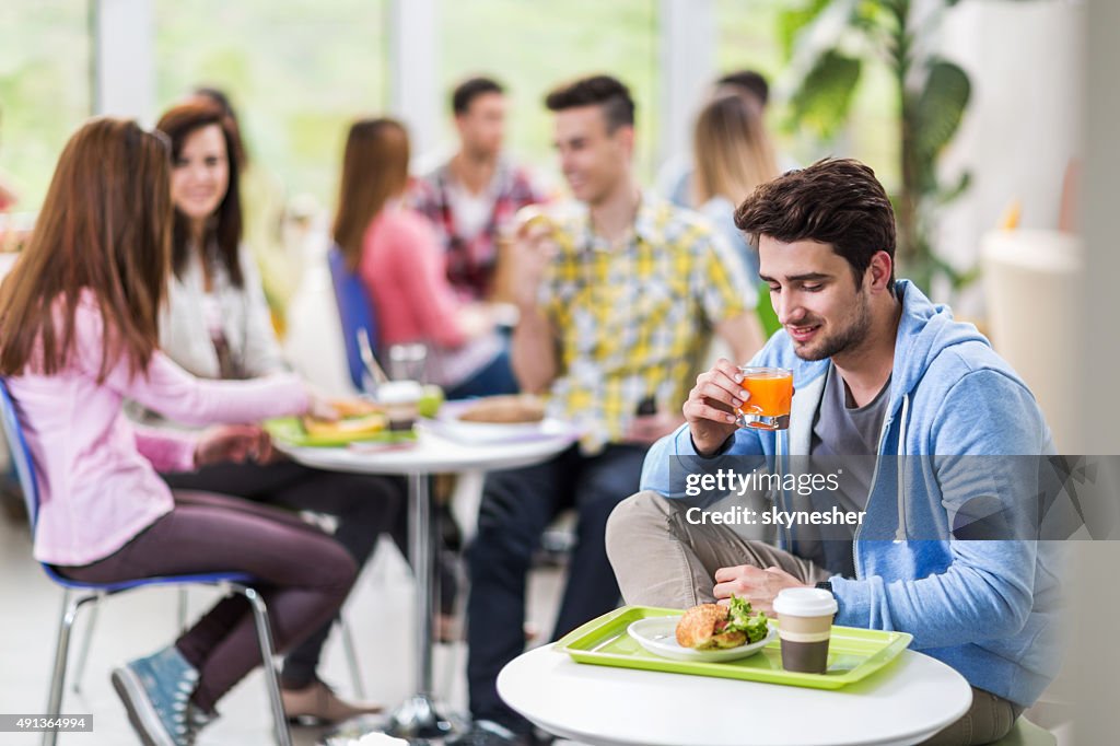 Smiling student on a lunch break drinking juice.