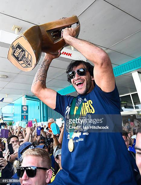 Johnathan Thurston of the Cowboys is hoisted onto the shoulders of Ben Hannant and Kane Linnett with the NRL trophy after arriving back at the...