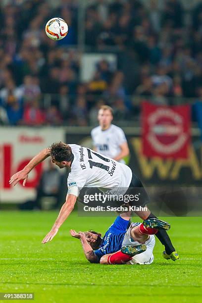 Marius Sowislo of 1. FC Magdeburg is tackled by Marc Heider of Holstein Kiel during the 3. League match between Holstein Kiel and 1. FC Magdeburg at...