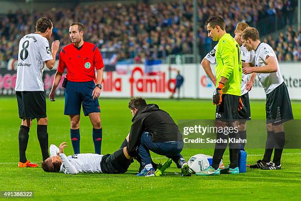 Injured Michel Niemeyer of 1. FC Magdeburg gets a treatment on the field of play during the 3. League match between Holstein Kiel and 1. FC Magdeburg...