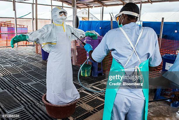 Healthcare worker cleans a colleague wearing Personal Protective Equipment at an Ebola Treatment Center in Coyah, Guinea, on Thursday, Sept. 10,...