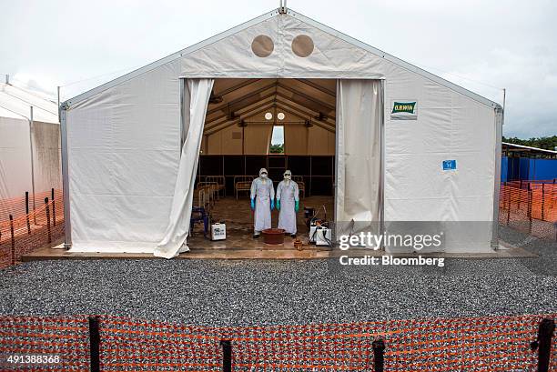 Healthcare workers wearing Personal Protective Equipment stand in a tent with patient beds at an Ebola Treatment Center in Coyah, Guinea, on...