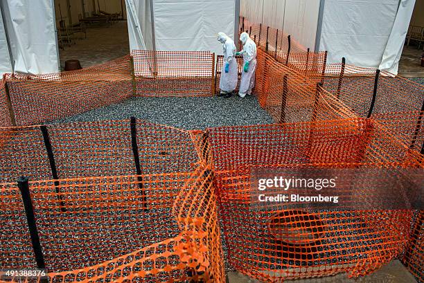 Healthcare workers wearing Personal Protective Equipment make their way to a tent with patient beds at an Ebola Treatment Center in Coyah, Guinea, on...