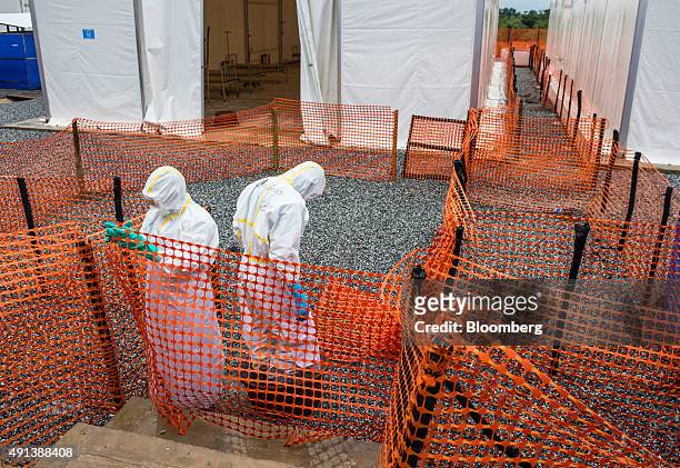 Healthcare workers wearing Personal Protective Equipment make their way to a tent with patient beds at an Ebola Treatment Center in Coyah, Guinea, on...