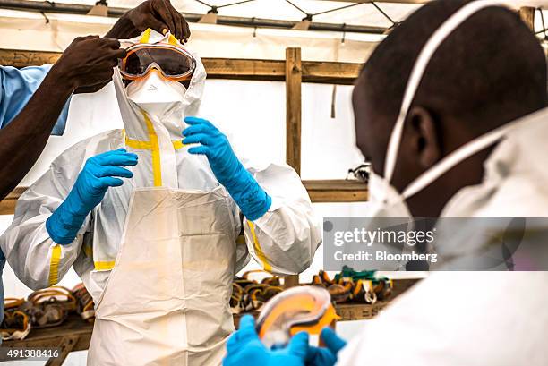 Healthcare worker assists a colleague to dress in Personal Protective Equipment at an Ebola Treatment Center in Coyah, Guinea, on Thursday, Sept. 10,...