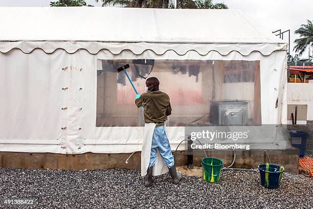 Healthcare worker washes a tent screen at an Ebola Treatment Center in Coyah, Guinea, on Thursday, Sept. 10, 2015. An Ebola epidemic and a slump in...