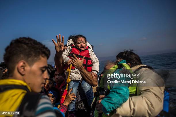 Refugees and migrants arrive on the shores of the Greek island of Lesbos after crossing the Aegean sea from Turkey on an inflatable boat on October...
