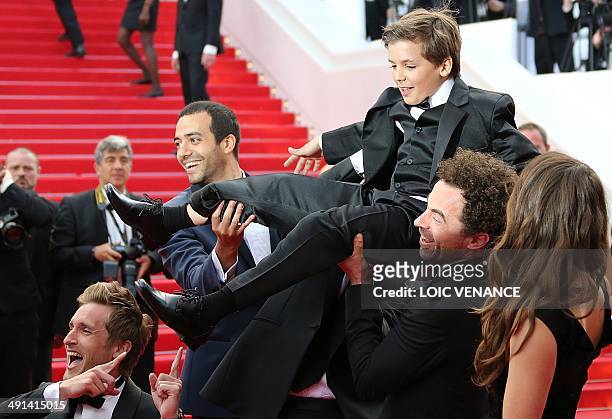 French actors Philippe Lacheau, Tarek Boudali and Gregoire Ludig carry actor Enzo Tomasini next to French actress Alice David as they arrive for the...