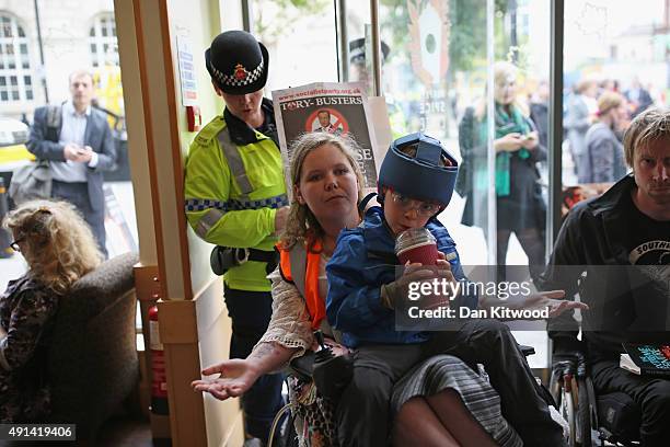 An anti-austerity protester in a wheelchair tries to prevent customers leaving a Starbucks cafe as protesters gather outside Manchester Central...