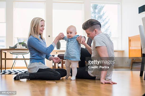 Lesbian couple assisting baby to walk at home
