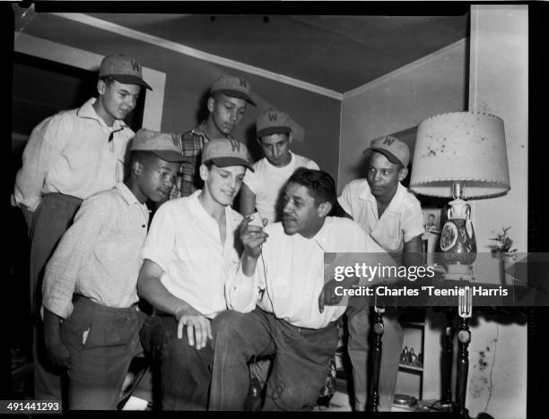 Baseball players wearing 'W' hats giving radio interview with Mal Goode in domestic interior, Pittsburgh, Pennsylvania, circa 1950-1970.