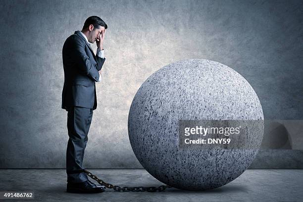 businessman burdened by a ball and chain - ball and chain stock pictures, royalty-free photos & images
