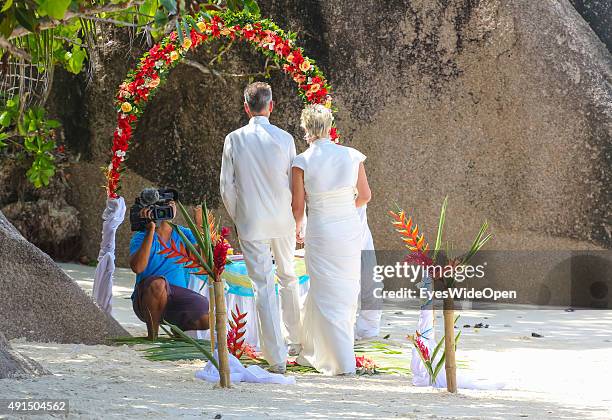 Marriage under palmtrees in white elegant clothes at the famous Source D´Argent Beach on October 01, 2015 in La Passe, La Digue, Seychelles.