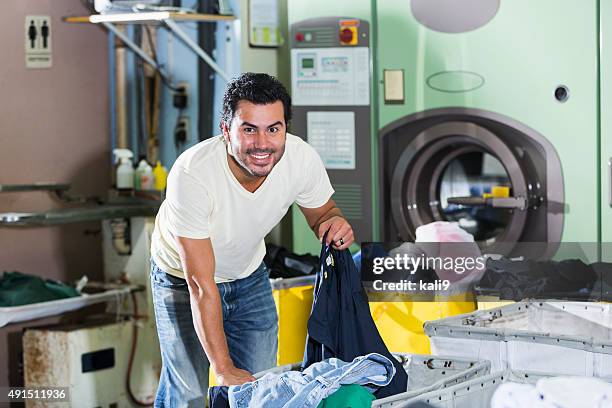 hispanic mann arbeitet in einem waschsalon - waschsalon stock-fotos und bilder