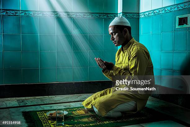 young muslim man praying, with folded hands - islam stock pictures, royalty-free photos & images