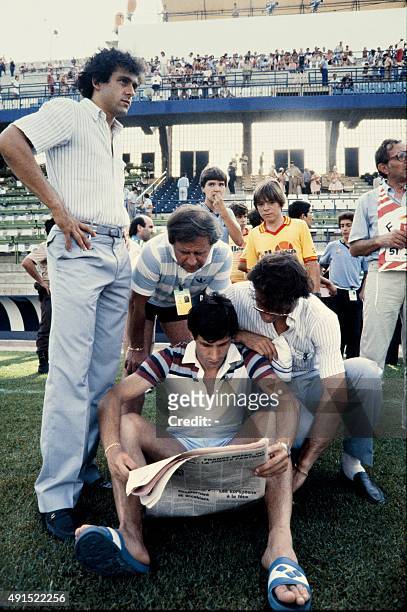 French defender Maxime Bossis reads the newspaper flanked by french midfielder Michel Platini France's manager Michel Hidalgo and French forward...