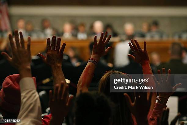 Members of the group Code Pink hold up their hands that are painted red while US Army Gen. John Campbell commander of the Resolute Support Mission...