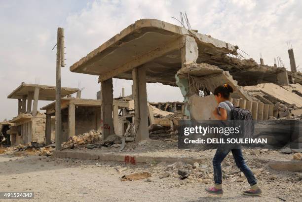 Syrian children walk past debris while heading to school on the second day of the new school year on October 6, 2015 in the Syrian Kurdish town of...