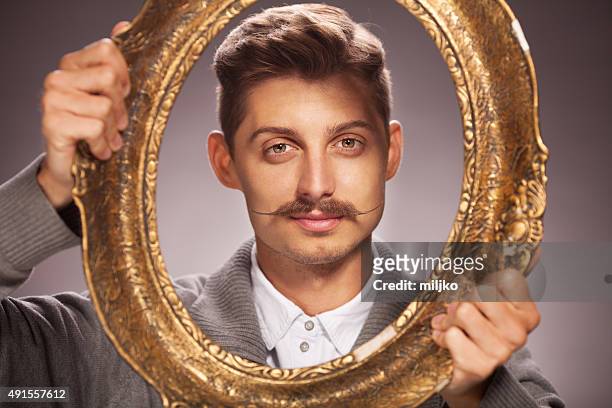 porträt eines jungen mannes mit schnurrbart - movember stock-fotos und bilder