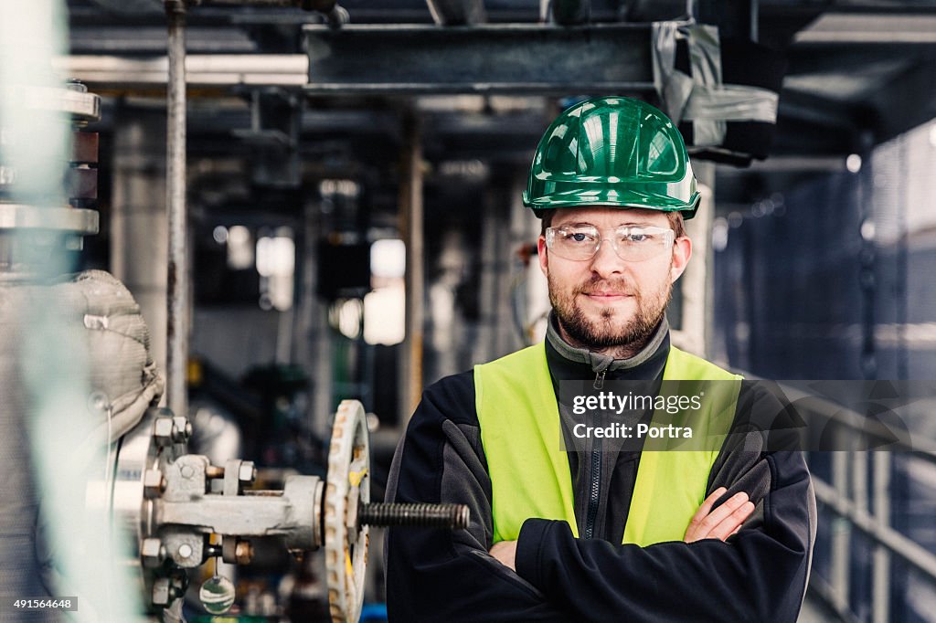 Male worker standing with arms crossed in factory