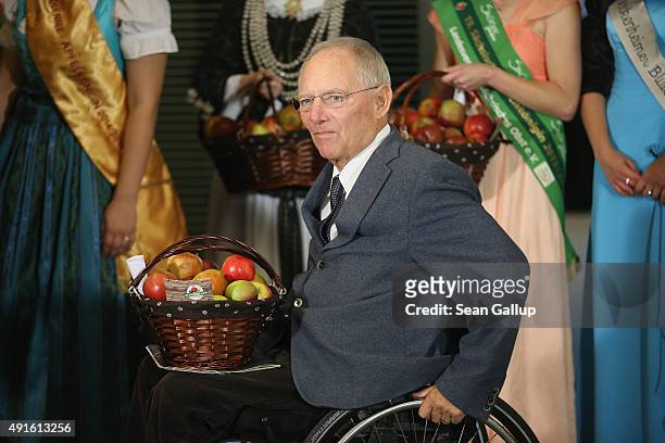 German Finance Minister Wolfgang Schaeuble receives a basket of apples before the weekly government cabinet meeting on October 7, 2015 in Berlin,...