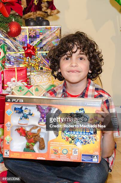 Real life Christmas scenes: Boy holding up newly unwrapped Christmas present. He is smiling as he holds up a brand new box containing the Skylanders...