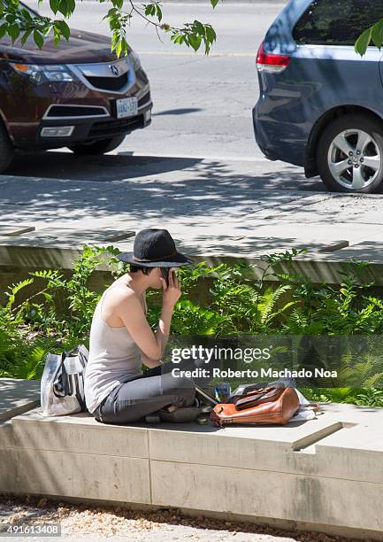 Smartphones in everyday life: Trendy cool hipster woman with phone and hat. Sitting on the curb and looking at the mobile phone.