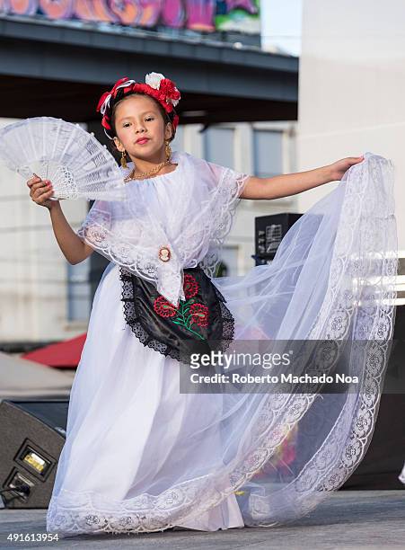 Young girl in white dress holding a hand-fan, performing Flamenco folk dance on stage at MexFest 2015 in Toronto. MexFest 2015 is celebration of all...