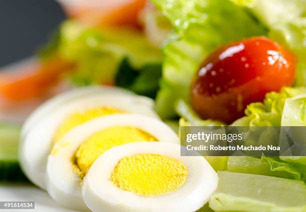 Deviled eggs with lettuce garnish. Slices of white and yellow deviled eggs sit on a plate beside iceberg lettuce and a cherry tomato.