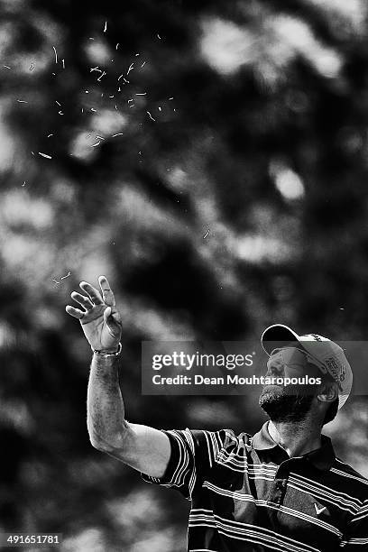 Alvaro Quiros of Spain throws grass in the air to judge the wind direction before he hits his second shot on the 10th hole during Day 2 of the Open...