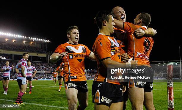 Tigers players Chris Lawrence, Luke Brooks, Cory Paterson and Robbie Farah celebrate a try during the round 10 NRL match between the...