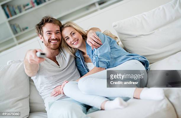 happy couple at home watching tv - couple tv stock pictures, royalty-free photos & images