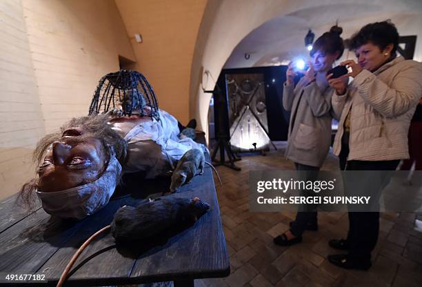 Visitors take photos of an installation of the exhibition "Torture and Execution in the Middle Ages" during its opening in Kiev on October 7, 2015....