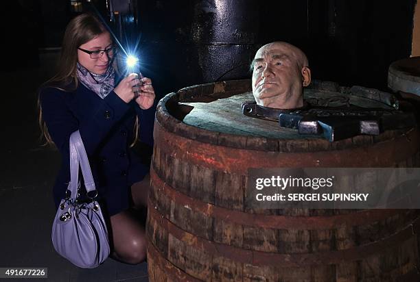 Visitor takes a photo of an installation at the exhibition "Torture and Execution in the Middle Ages" during its opening in Kiev on October 7, 2015....