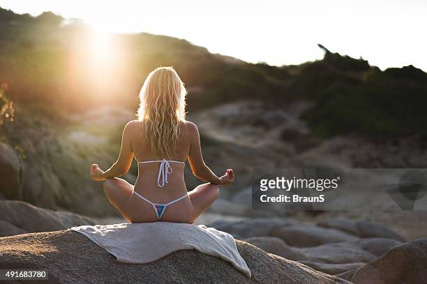 rückansicht einer frau ausübung yoga auf dem rock. - thongs stock-fotos und bilder