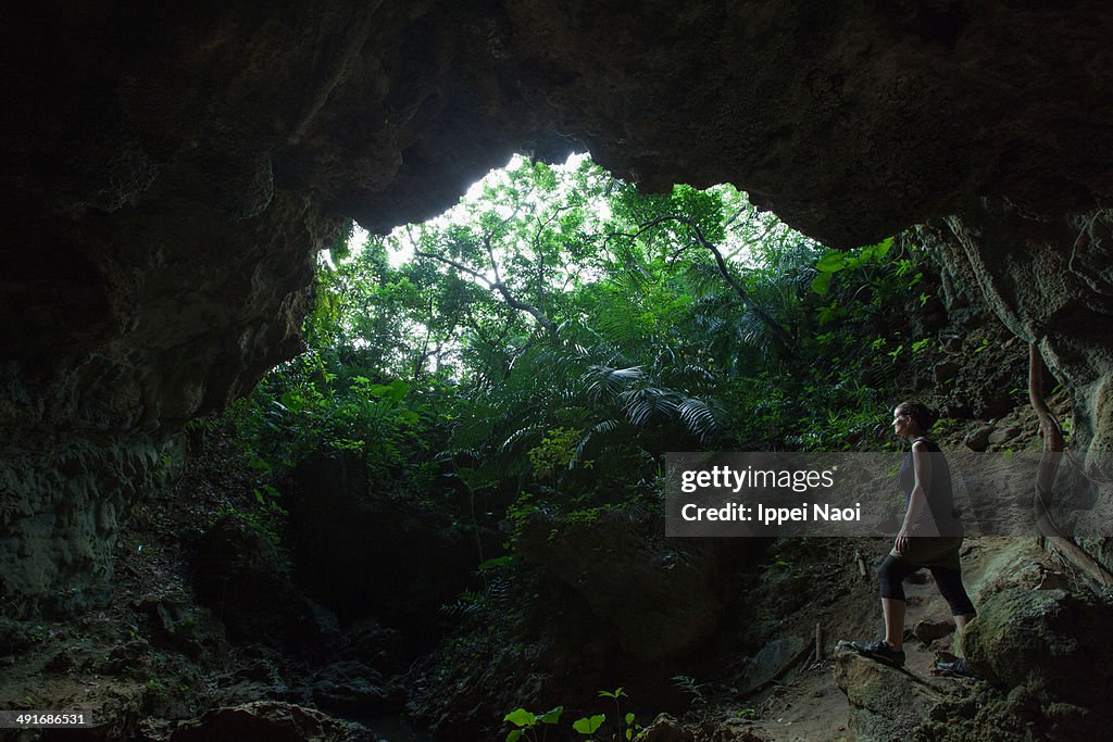 Woman standing inside a jungle cave, Iriomote