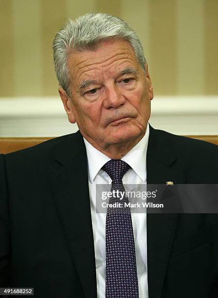 German President Joachim Gauck listens to US President Barack Obama speak to the media during a meeting in the Oval Office at the White House October...