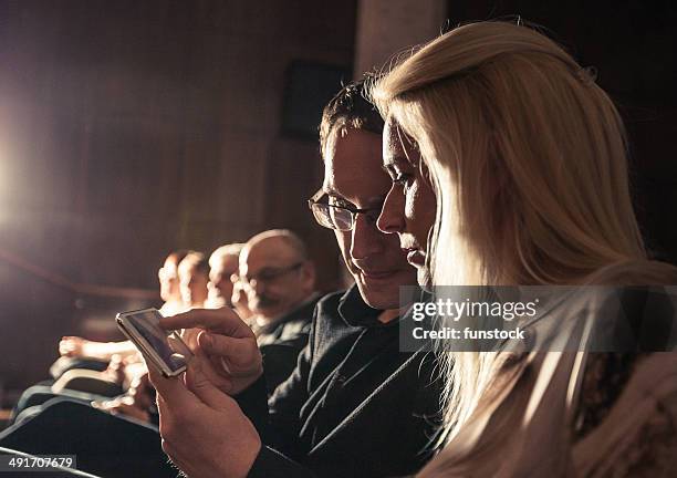 young couple using smartphone between theatre show - klassiek theater stockfoto's en -beelden