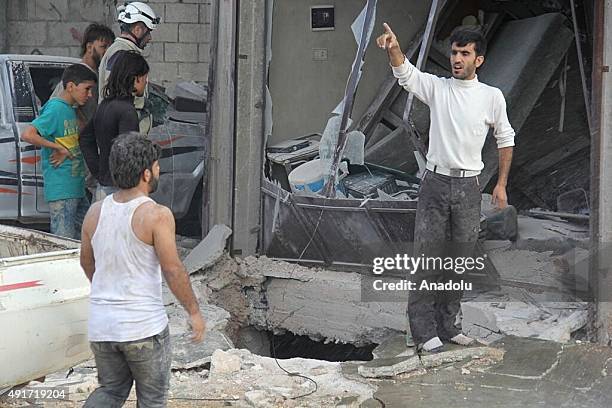 Residents gather outside the destroyed buildings after Russian air strikes in Maasaran town, Idlib, Syria on October 07, 2015.