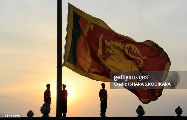 Sri Lankan soldiers stand at attention as their national flag is lowered as part of a daily ceremony at the Galle Face Green promenade in Colombo on...