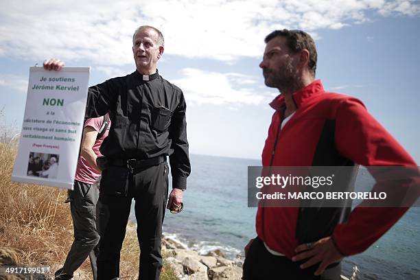 French priest Patrice Gourrier holds a poster supporting former trader Jerome Kerviel near the French border on May 17, 2014 outside Vintimille ....