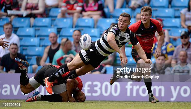 Jack Owens of Widnes Vikings offloads underpressure from Danny Williams and Jake Mullaney of Salford Red Devils during the Super League match between...